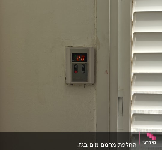 תרמוסטט דיגיטלי על קיר ליד תריסים